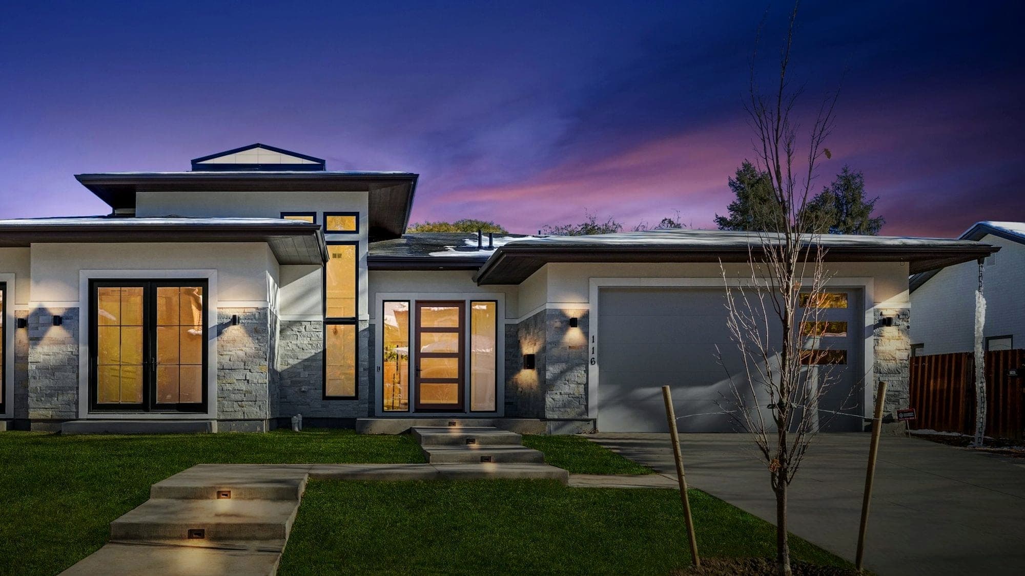 A modern house with its lights on at dusk