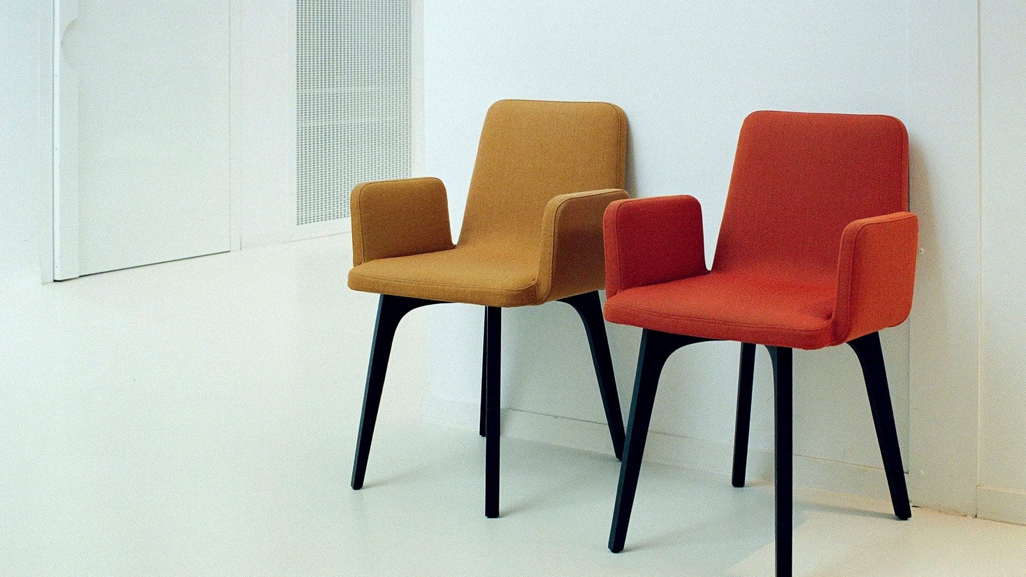 Two empty chairs waiting against a white wall