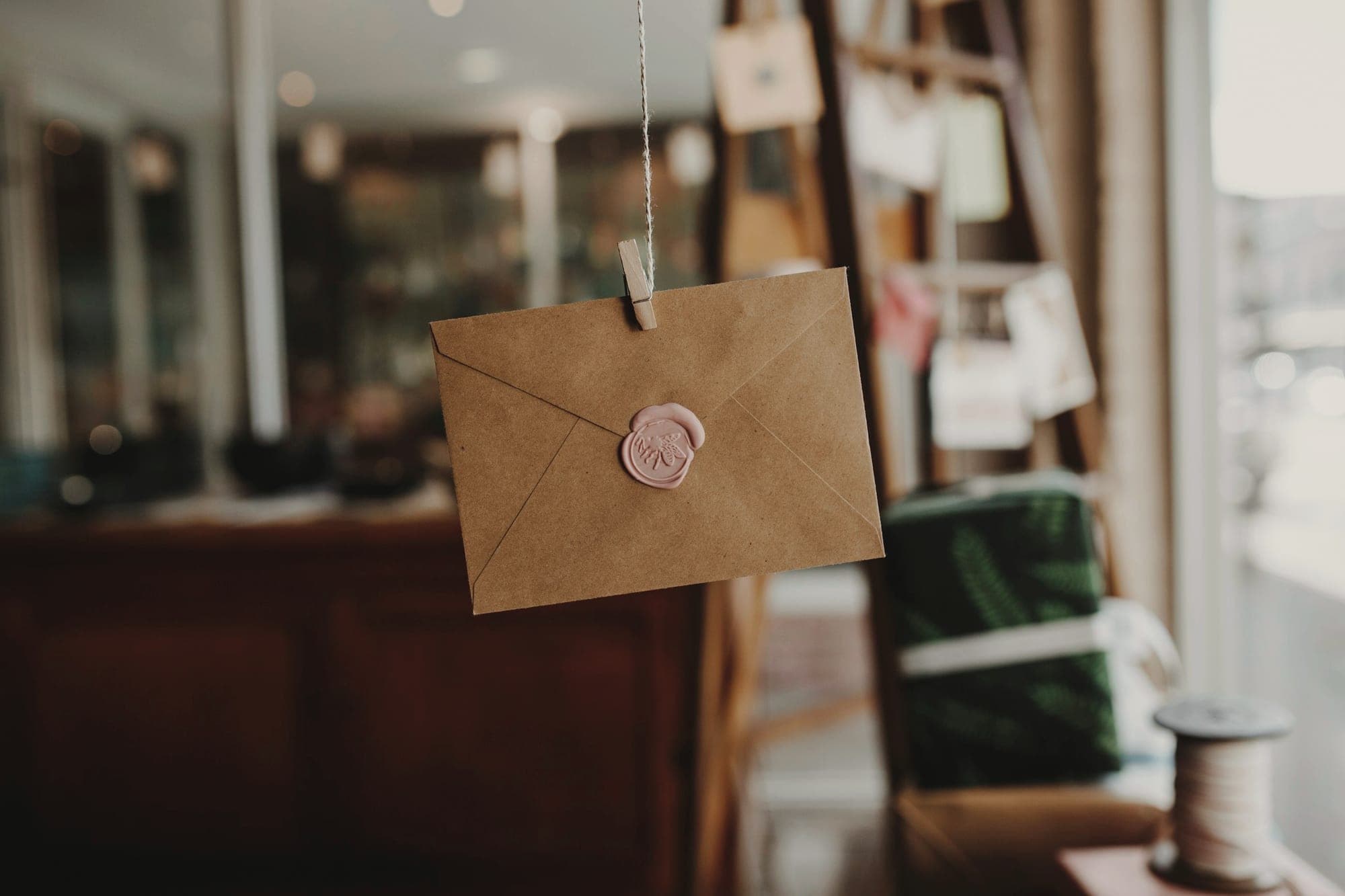 A sealed brown envelope hanging from a peg on a string, waiting to be sent.