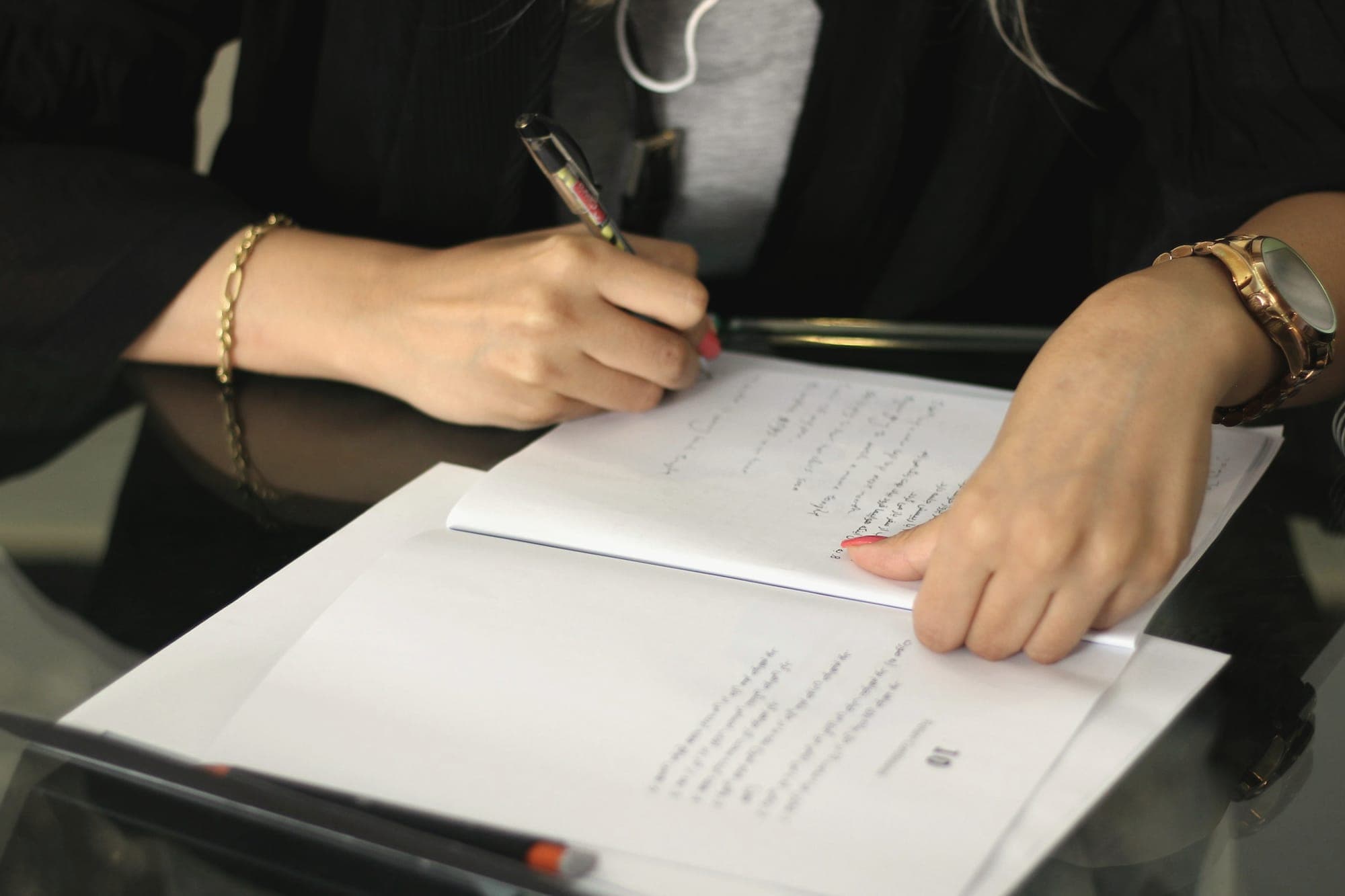 Hands writing notes on printed pages