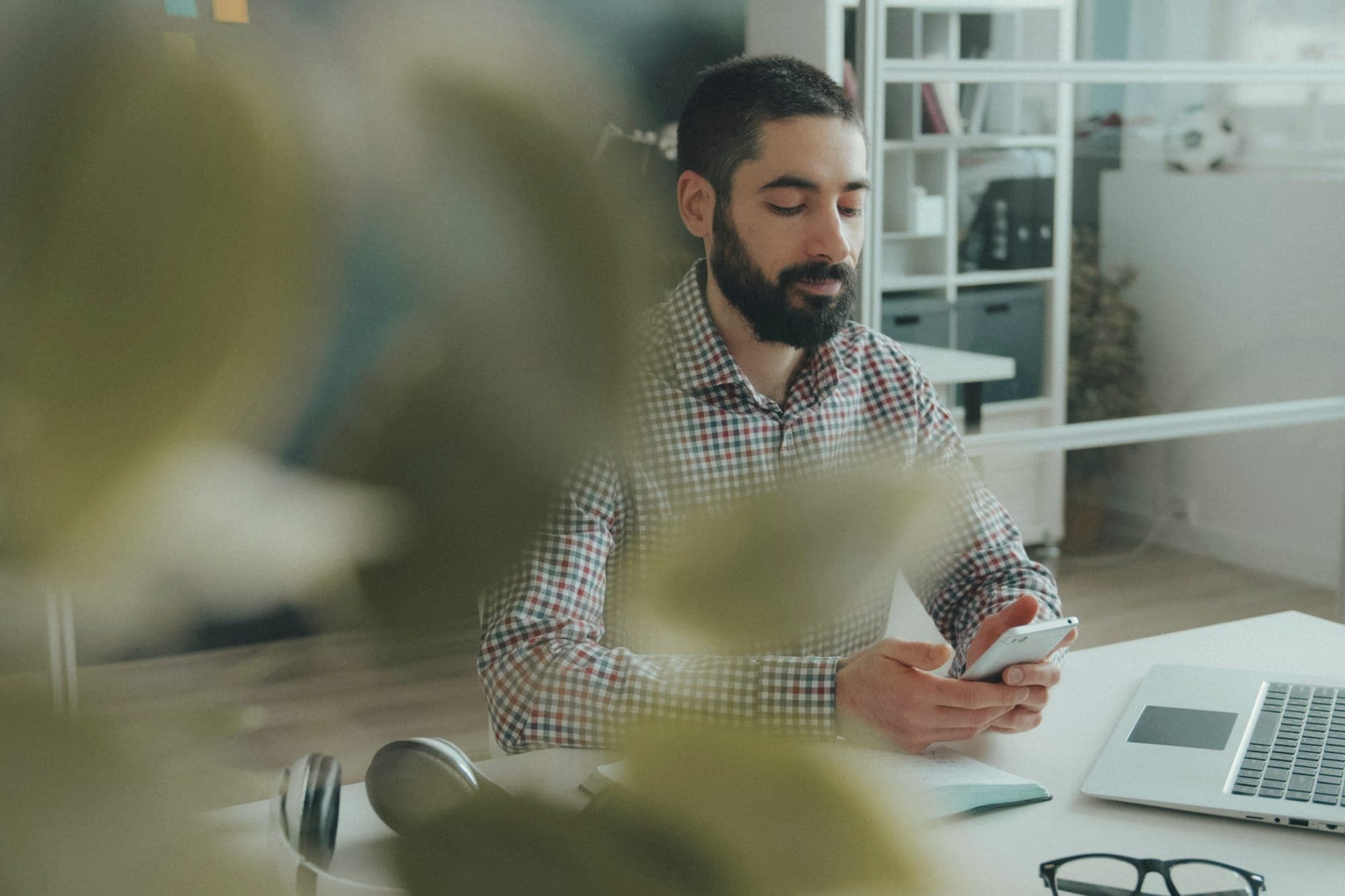 A man reading a message on his phone at his desk