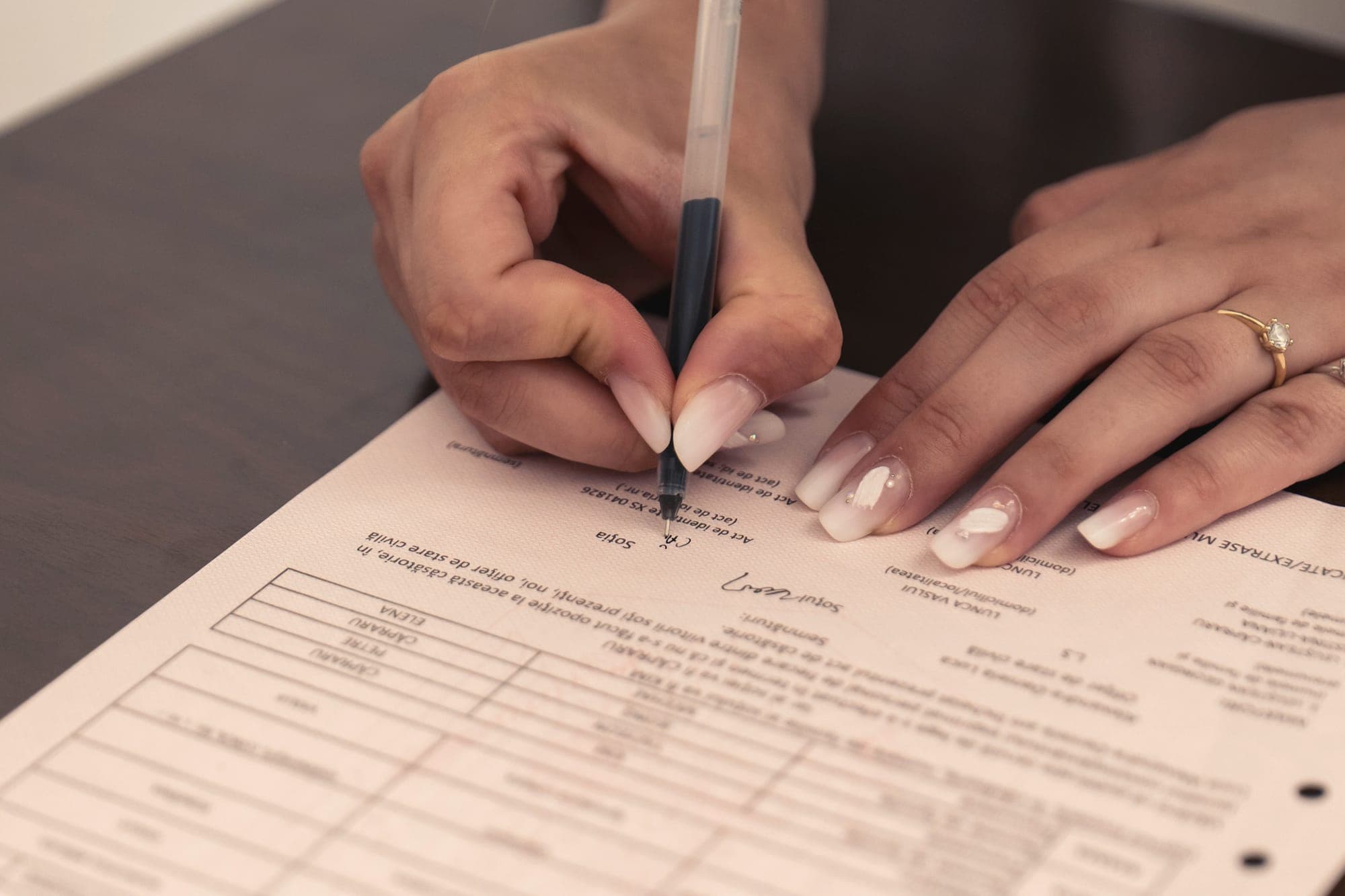 A hand signing a printed form with a black pen